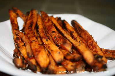 a plate of orange colored sweet potato fries with dark edges