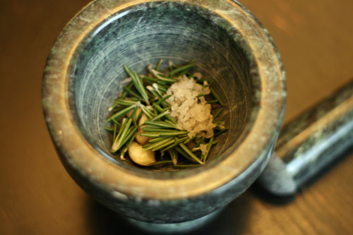 Seasonings for Lemon Rosemary Vinaigrette Recipe are shown in a mortar pestle.