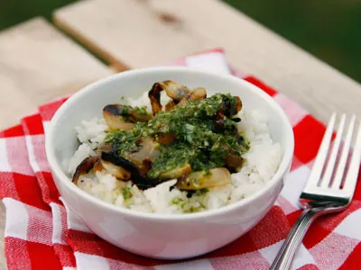 Basil chimichurri is shown drizzled on a bowl of rice, onions and other ingredients.