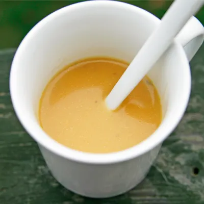 Gravy is shown in a white coffee cup with a white spoon inside.