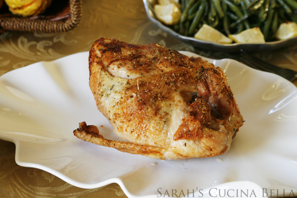 This shows a cooked bone-in turkey breast on a white platter surrounded by platters of side dishes like green beans