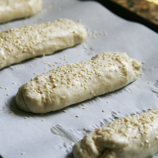 This photo shows Sesame Rolls Ready to Bake on a parchment-lined baking sheet.