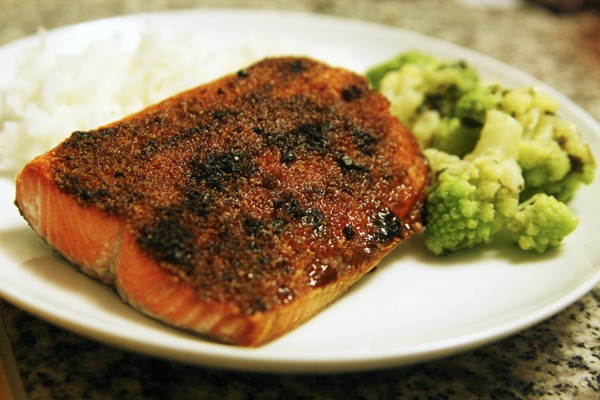 Broiled Sockeye Salmon is plated with green vegetables and white rice.