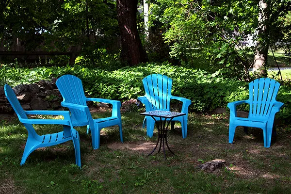 Four teal plastic chairs sit outside around a small table.