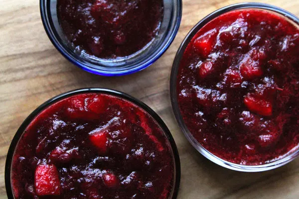 Three bowls of cranberry sauce sit on a cutting board. If you are having a small Thanksgiving, you could freeze part of your cranberry sauce for later.