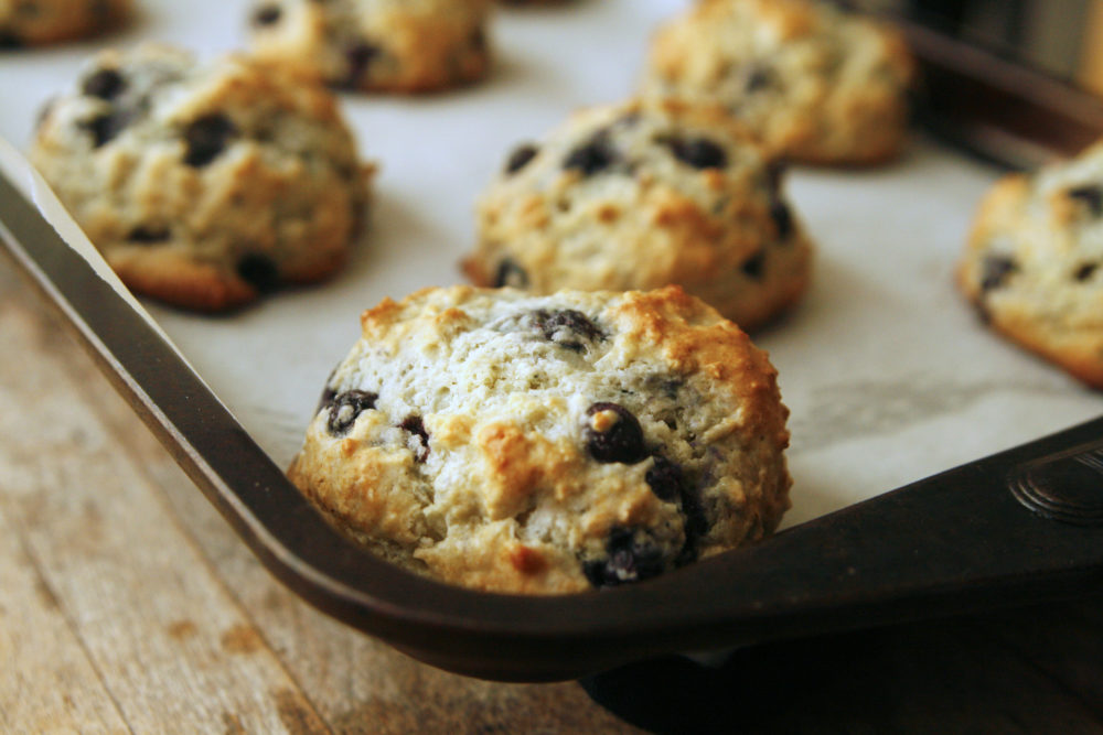 A rimmed baking sheet covered in parchment paper with Blueberry Muffin Tops.