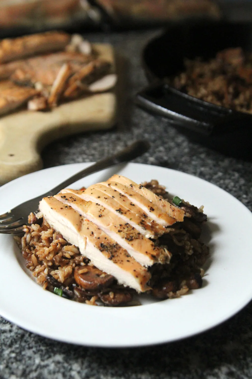 A white plate of Balsamic Mushroom Rice with Shallots topped with chicken