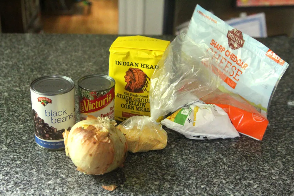 Ingredients for Black Bean Corn Enchilada Pie are shown on a gray granite countertop.