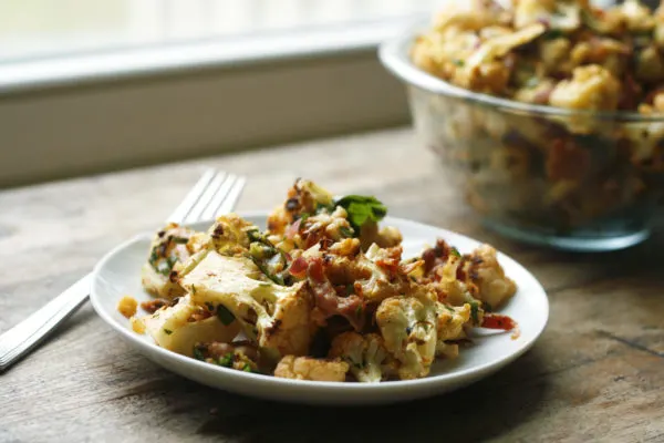 Roasted Cauliflower Salad with Bacon and Lovage makes a great side dish or can be eaten as a meal. Here, it's shown on a plate in the foreground and in a bowl in the background.