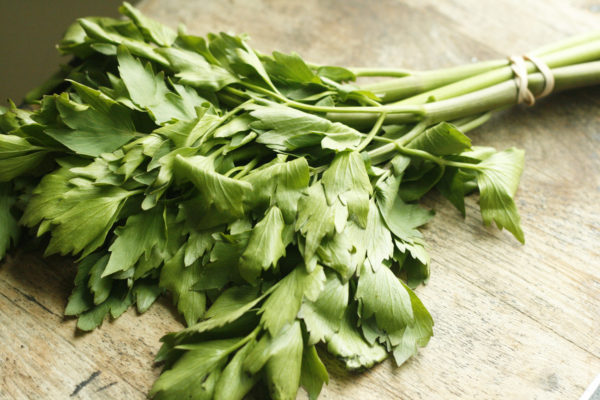 A bunch of leafy lovage sits on a butcher block.