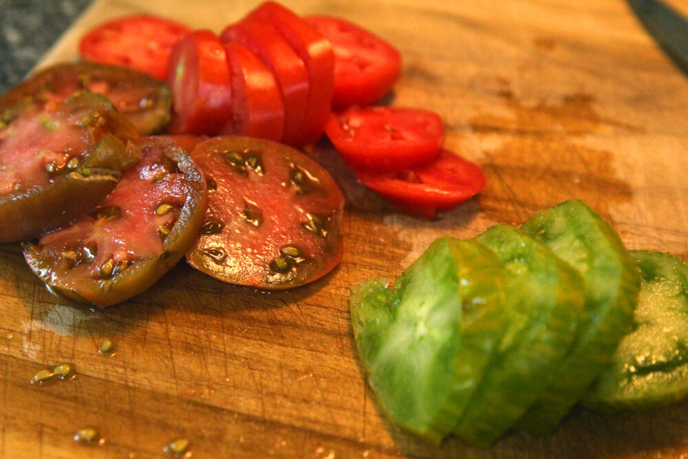 sliced tomatoes are shown on a cutting board.