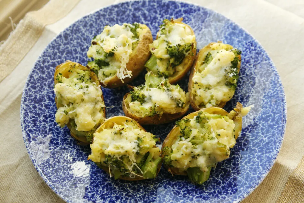 Broccoli and cheddar filled potatoes on a blue and white plate.
