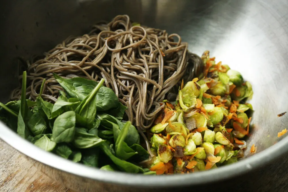 Sesame Soba Noodles with Brussels Sprouts in progress shown in a silver bowl.