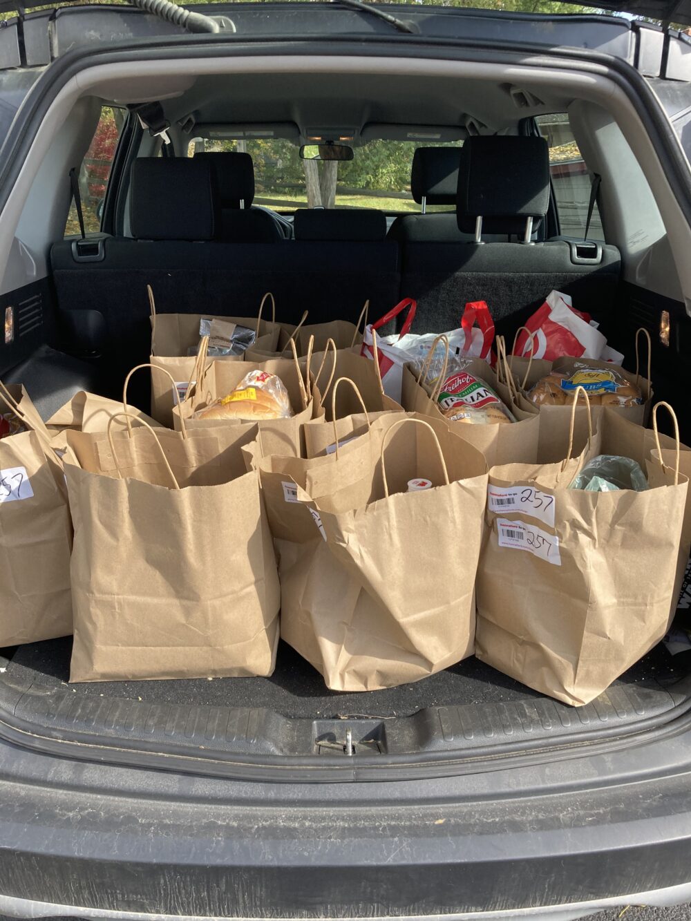 Paper grocery bags from a grocery pickup order are shown in the trunk of a vehicle.