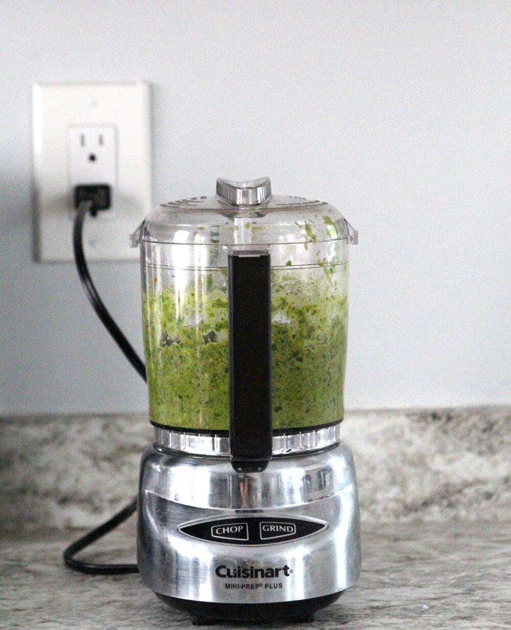 A Cuisinart Mini-Prep Plus sits on a counter. The bowl is filled with green pesto.