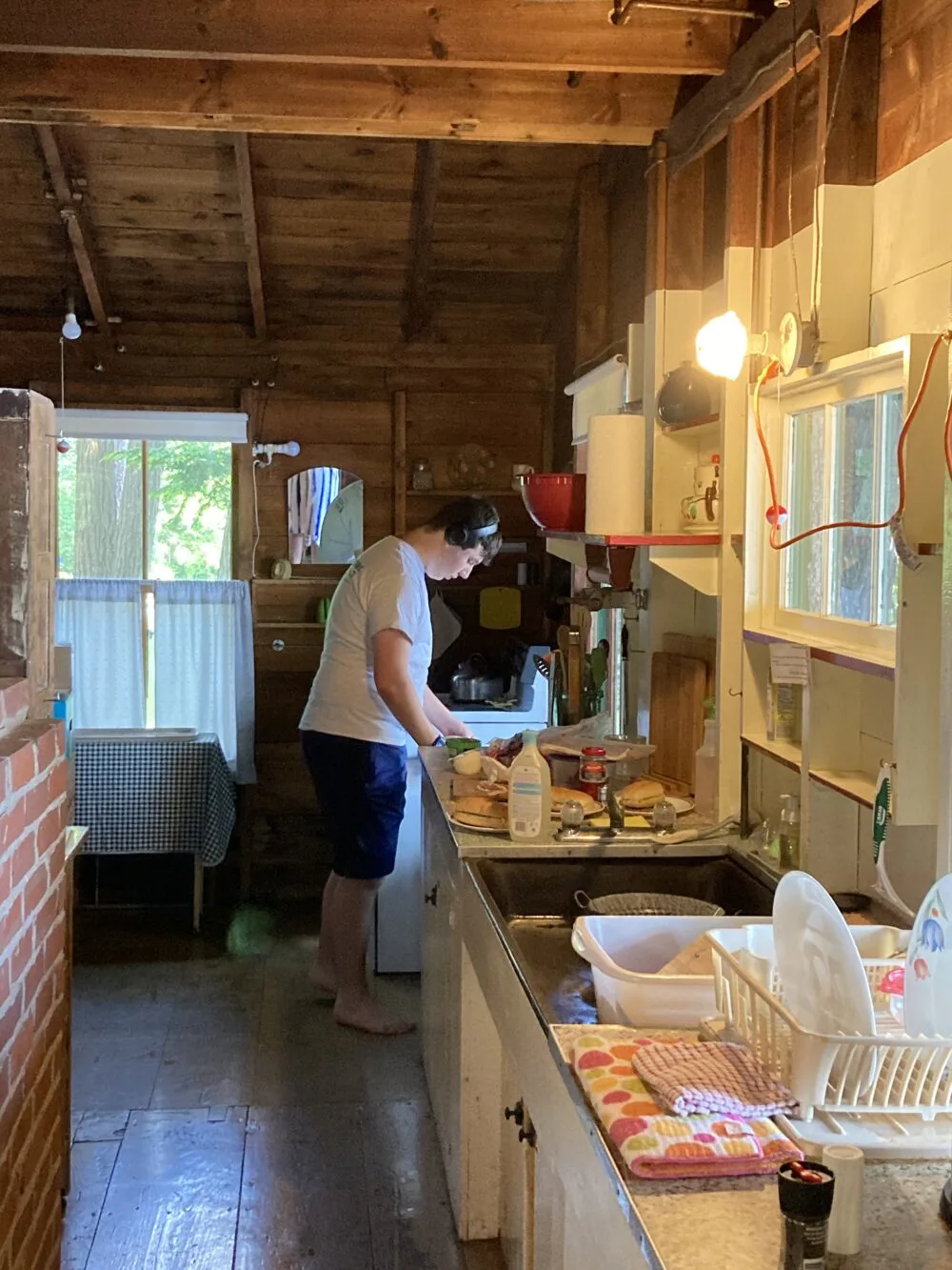 A young man is shown making lunch in a rustic rental cabin kitchen.