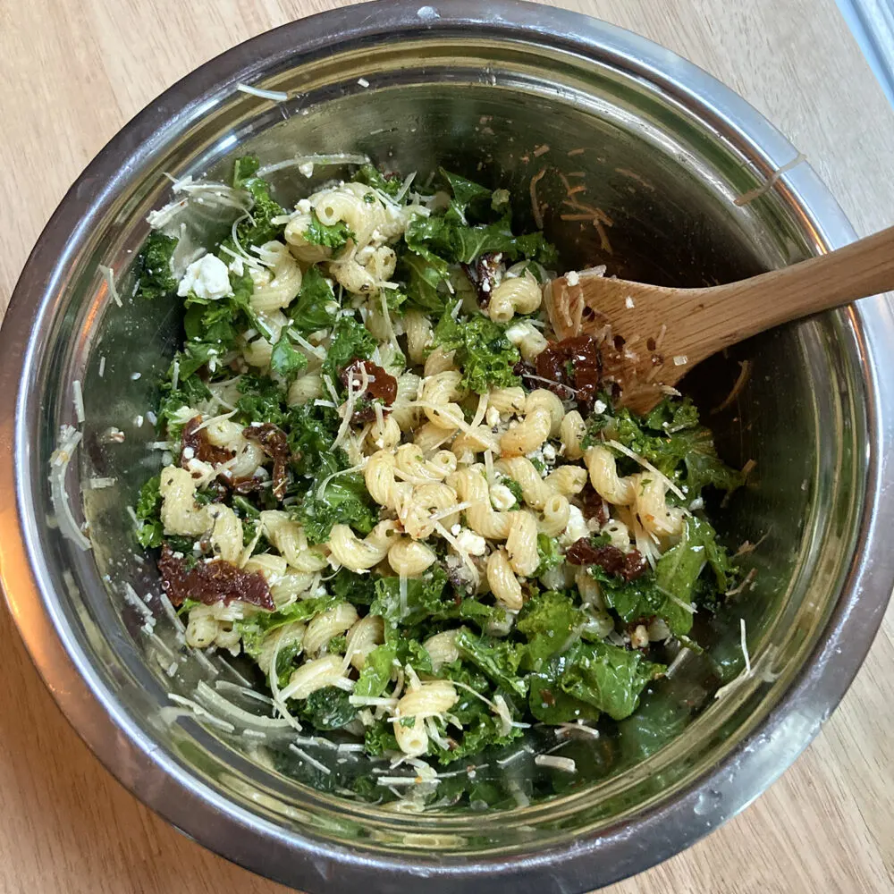 Kale Feta Pasta Salad is shown in a metal mixing bowl.